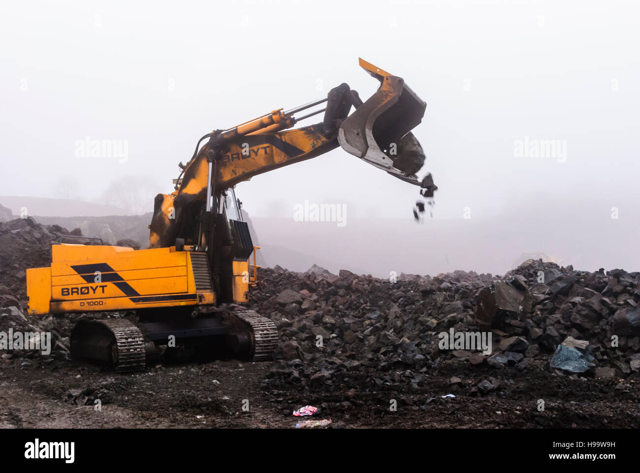 BROYT escavatori A-broyt-tracked-loader-dumps-a-bucket-of-rocks-in-a-quarry-in-heavy-H99W9H