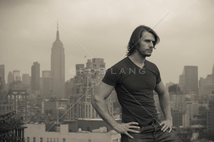 Boate WolfNeon Portrait-of-a-man-wtih-long-hair-standing-on-a-rooftop-in-New-York-City-overlooking-the-Empire-State-Building