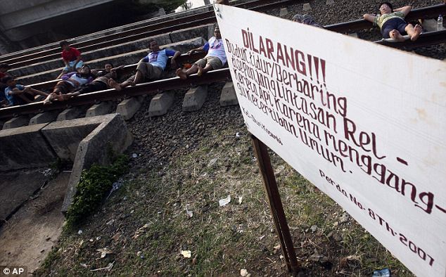 بالصور  والفيديو // فى اندونيسيا الاعتصام بالنوم فوق قضبان القطارات من اجل العلاج (( خاص أمواج )) Article-0-0D43E9C100000578-561_634x394