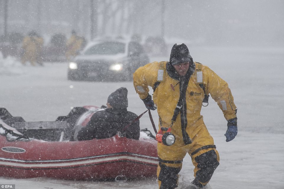 El bombero Justin Plaza arrastra a un automovilista rescatado a tierra firme, en Boston, Massachusetts el jueves