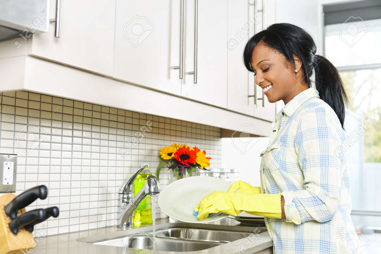 Comment devenir moins paresseux ? 9417825-Smiling-young-black-woman-washing-dishes-in-kitchen-Stock-Photo