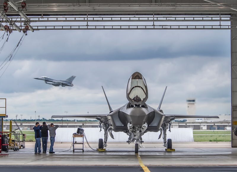 افضل صور للمقاتله F-35  An-f-35a-sits-in-a-station-on-the-flight-line-as-an-f-16-takes-off-behind-it