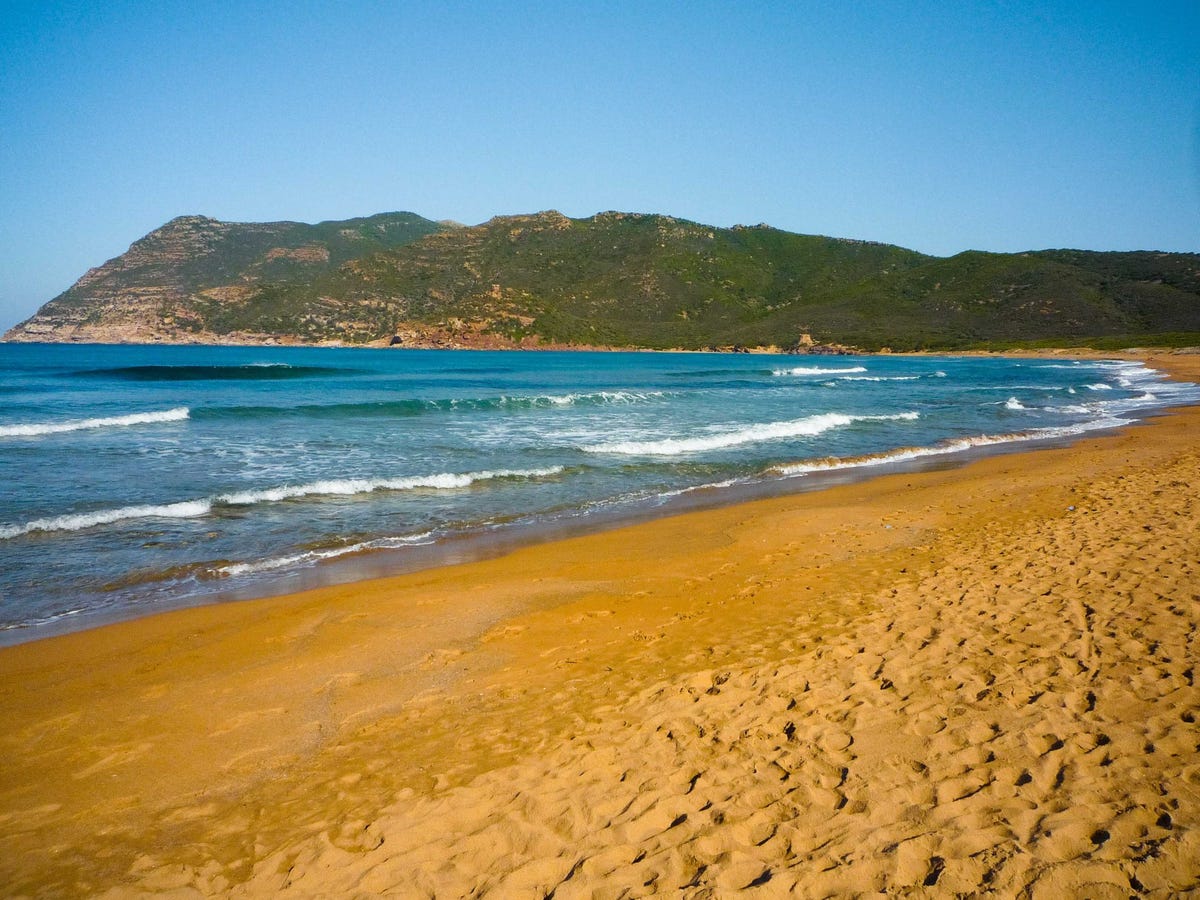 Những bãi biển cát màu rất đẹp trên thế giới Porto-ferro-in-sardinia-italy-hosts-bright-orange-colored-sand-that-is-a-result-of-the-areas-orange-limestone-crushed-shells-and-volcanic-deposits-while-youre-there-head-to-the-65-foot-high-sand-dunes-behind-the-beach