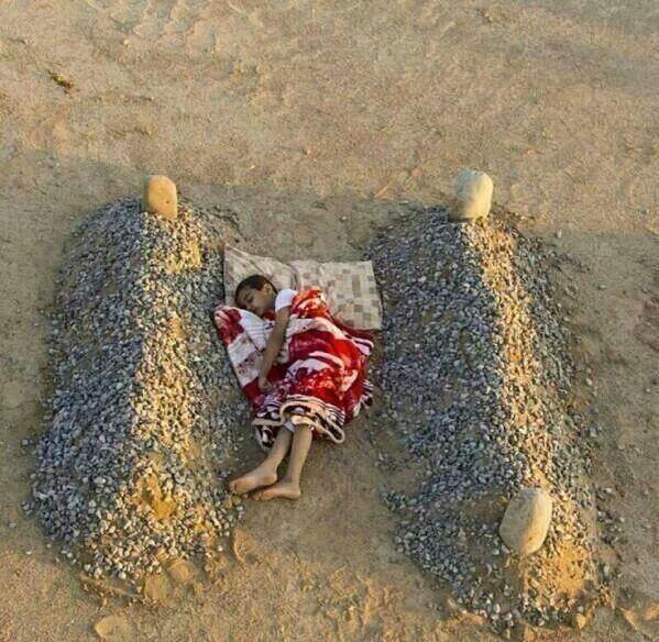 بالصور.. طفل سوري ينام حيًّا بين قبرَيْ والديه!  184493236