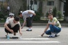 These out-of-uniform trafficgirls stay busy, possibly volunteer work painting a crosswalk on a Pyongyang street.